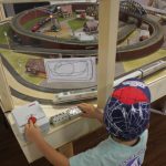 Child controlling a model train at Small Worlds Dubai interactive play table