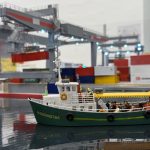 Miniature container ship named Margaretha at Small Worlds Dubai, set against a detailed model of a container port with cranes and cargo containers
