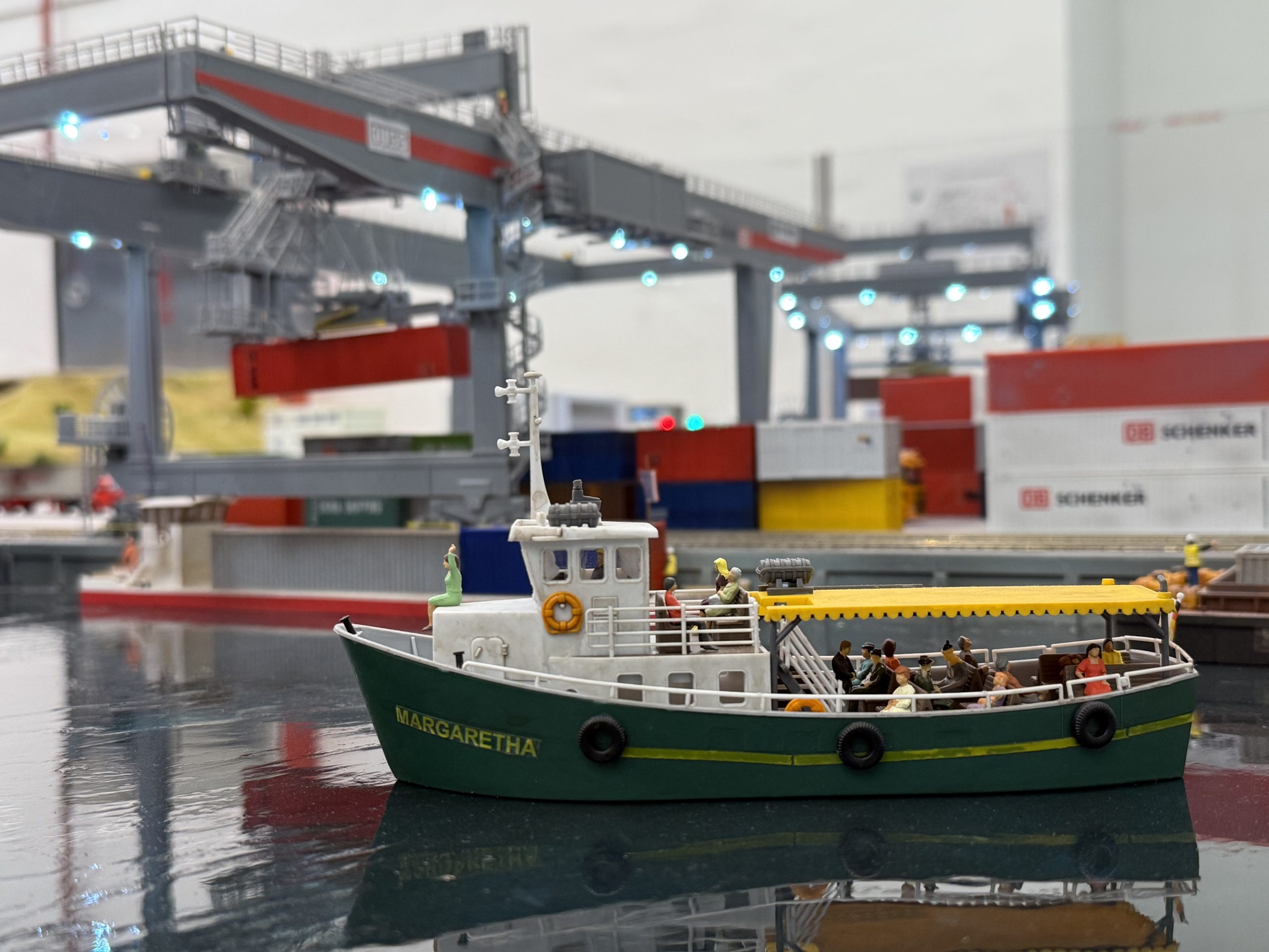 Miniature container ship named Margaretha at Small Worlds Dubai, set against a detailed model of a container port with cranes and cargo containers