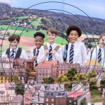 Group of school children in uniform smiling in front of a detailed miniature European city model at Small Worlds Dubai